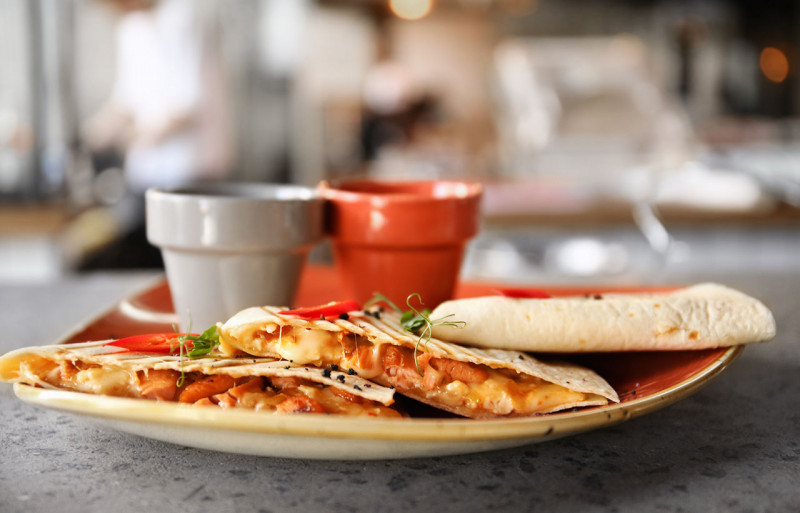 Quesadillas on a plate with sauces in the background