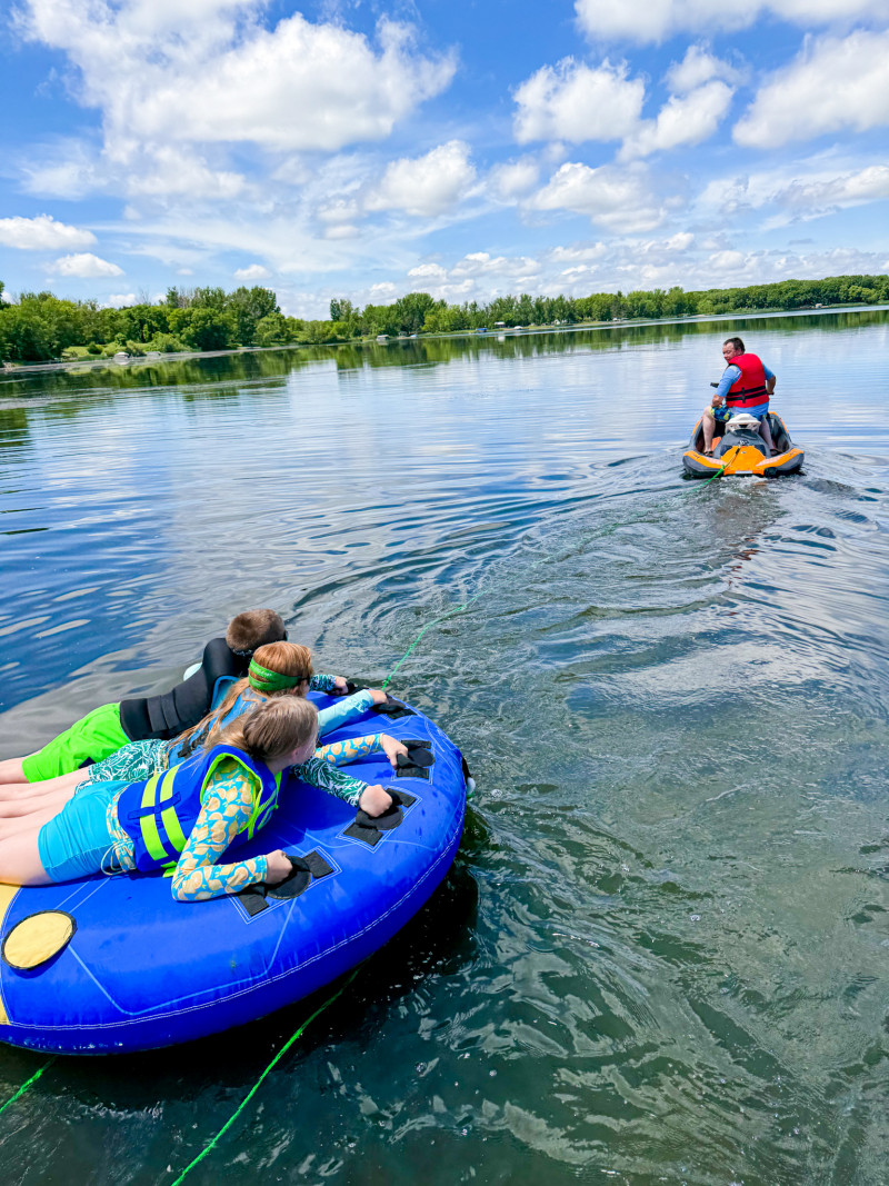 Kids tubing behind jet ski. Minnesota Summers For Our Farm Family.